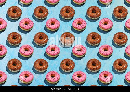 Seamless pattern of donuts with pink and brown glaze on a blue background. Stock Photo