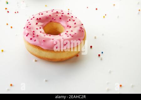Pink donut with icing, sprinkles on white background. Stock Photo