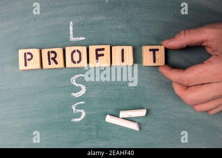 Profit and Loss concept. Text from letters of the wooden alphabet on a green chalk board. Stock Photo