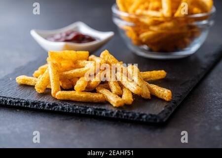 French fries. Salted snack. Potato chips on cutting board. Stock Photo