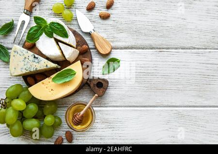 Different types of cheese with snacks on an white old wooden table Stock Photo