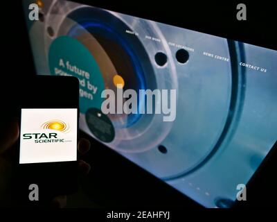 Person holding smartphone with logo of Australian hydrogen company Star Scientific Limited on screen in front of website. Focus on phone display. Stock Photo