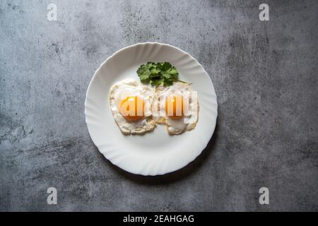 Egg poach sunny side up a healthy food ingredient on a plate. View from top, selective focus. Stock Photo