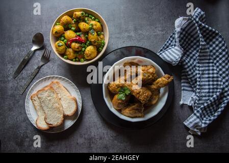 Indian full meal of chicken in gravy, dum aloo or steam potatoes and bread on a background. Top view, selective focus. Stock Photo