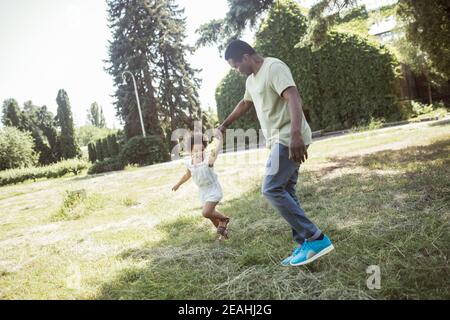 Cute curly kid sitting having great time with her dad Stock Photo