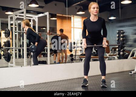 Close up of young fit woman doing barbell exercises in gym. Healthy lifestyle concept. Selective focus Stock Photo
