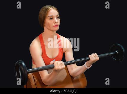 Close up of young fit woman doing barbell exercises in gym isolated on black background. Healthy lifestyle concept. Selective focus Stock Photo