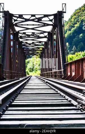 Railway bridge. Railroad tunnel with red rusty bars. Abandoned Rail Bridge. Looking down thetracks on a train bridge Stock Photo