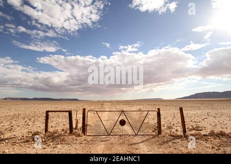 A rusty old farm gate and fence in the middle of the desert Stock Photo