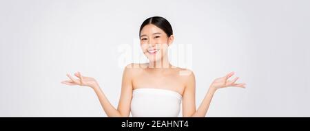 Beauty shot of young Asian girl with glowing face skin opening empty hands on white banner background Stock Photo