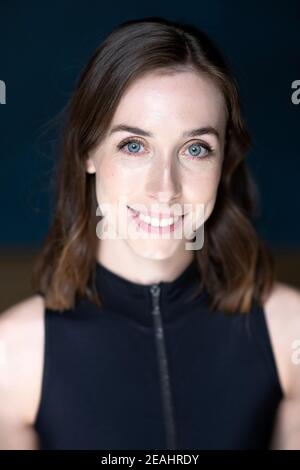 Head and shoulders portrait of young woman with shoulder length brown hair wearing a black top Stock Photo