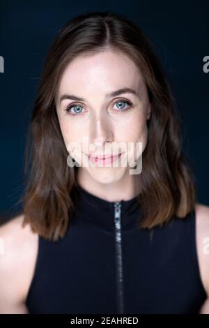 Head and shoulders portrait of young woman with shoulder length brown hair wearing a black top Stock Photo