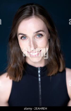 Head and shoulders portrait of young woman with shoulder length brown hair wearing a black top Stock Photo