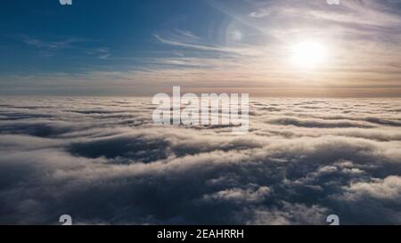 Beautiful sunset sky above clouds with dramatic light. Cabin view from airplane Stock Photo