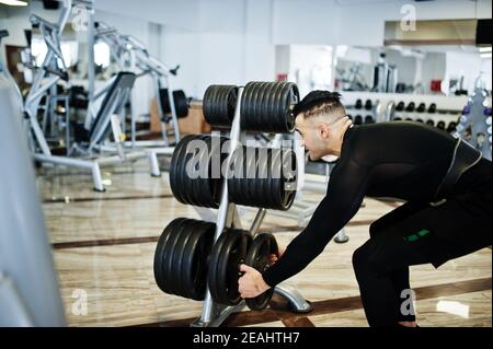 Muscular arab man training with dumbbells in modern gym. Stock Photo