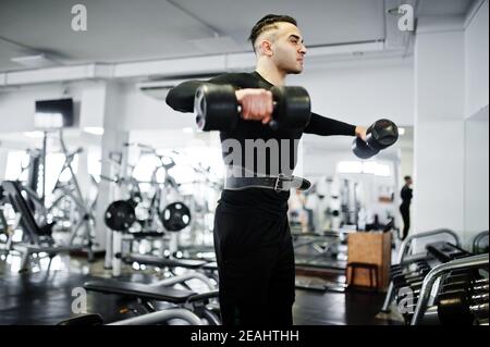Muscular arab man training with dumbbells in modern gym. Stock Photo