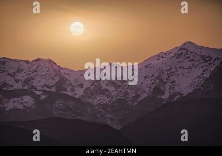 Apuane alpi or Apuan alps snowy mountains in winter in a red susnet. Garfagnana, Tuscany, Italy. Stock Photo