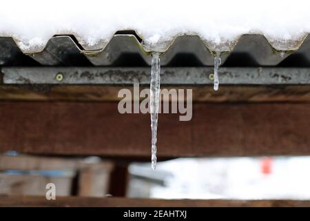 The snow on the roof melts and forms ice icicles Stock Photo
