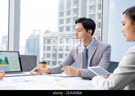 Young Asian businessman presenting corporate information chart on laptop computer in the meeting at city office Stock Photo