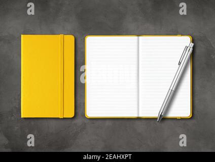 Yellow closed and open lined notebooks with a pen on dark concrete background Stock Photo