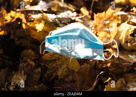 medical breathing mask lies on autumnal yellow maple leaves. leaves on the street that show autumn and the cold season. Corona protection Stock Photo