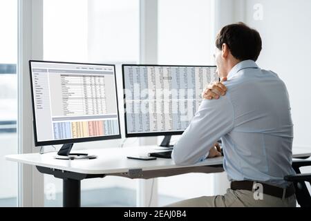 Businessman Having Shoulder Pain While Working At Computer Desk Stock Photo