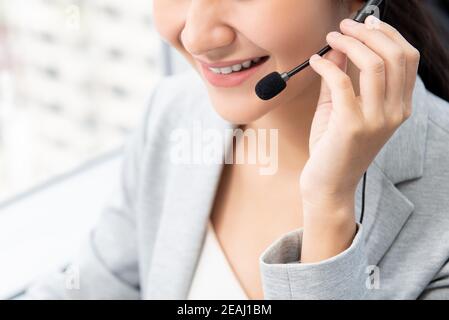 Close up of smiling woman customer service operator wearing microphone headset in call center Stock Photo