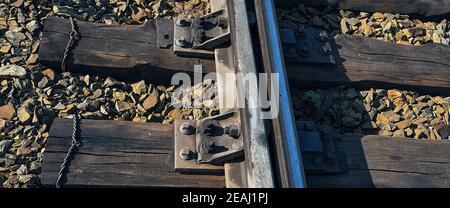 Single rail as part of a railway. Wooden sleepers and gravel are also visible. Stock Photo