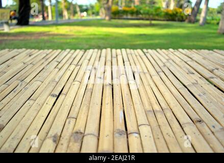 Bamboo wooden board front template. Empty tabletop nature planks with bokeh, blurred, defocused of public park, outdoor texture abstract background. Stock Photo