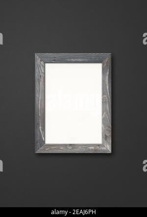 Old rustic wooden picture frame hanging on a black wall Stock Photo