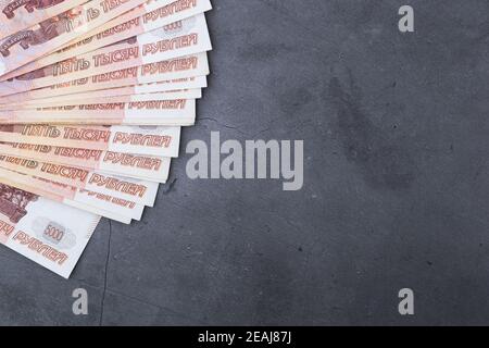 Big stack of Russian money banknotes of five thousand rubles lying fan on a grey cement background. Stock Photo
