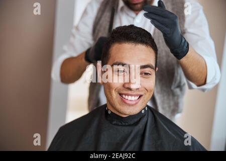 Attractive male is getting a modern haircut in barber shop Stock Photo