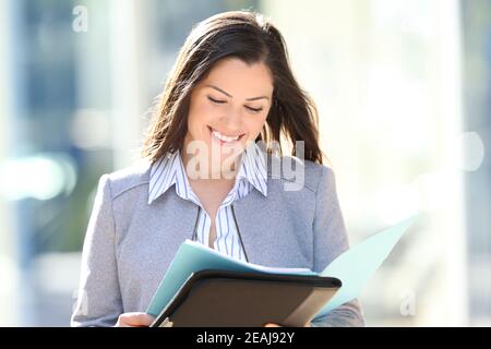 Happy entrepreneur reading report in the street Stock Photo