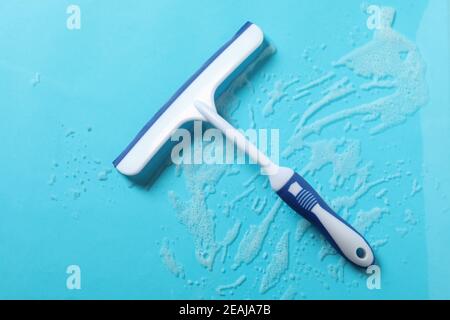 Window сleaning squeegee on blue background with foam Stock Photo