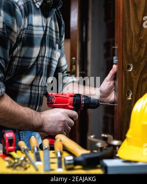 Carpenter at work repairs and installs the door lock. Carpentry. Stock Photo