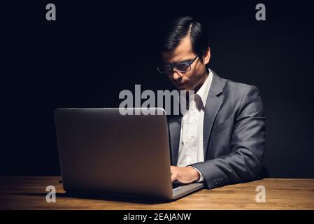 Focused young businessman working on laptop computer overtime in office at night Stock Photo