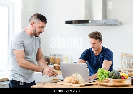 Young gay couple spending morning time together in their kitchen at home for lgbt lifestyle concept Stock Photo