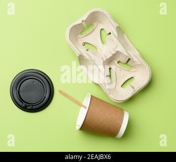 disposable paper cups from brown craft paper and recycled paper holders on a green background Stock Photo
