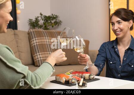 Two women friends sitting by table and eating sushi. Family, friendship and communication concept. Stock Photo