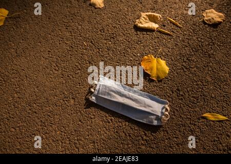 Used surgical mask lying on the ground Stock Photo