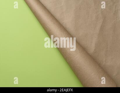 folded corner of a roll of brown paper on a green background Stock Photo
