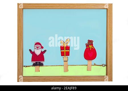 Christmas decorations element. Closeup of a wooden frame with clothesline and clothes pegs with a santa claus, a bear and a gift box isolated on a white background. Stock Photo