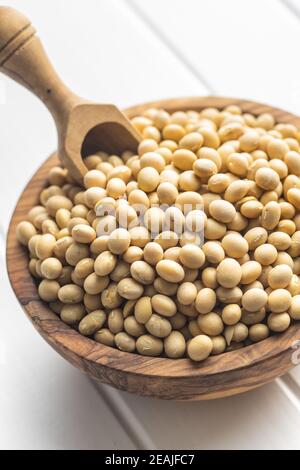 Dried soy beans in wooden bowl on white table. Stock Photo