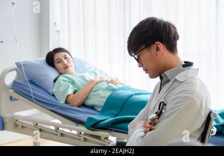 Tired Doctor in white uniform napping at hospital ward for caring patient. Stock Photo