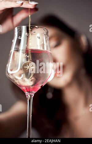 Drops of red blood paint in a glass of water, a woman looks at the glass. Stock Photo