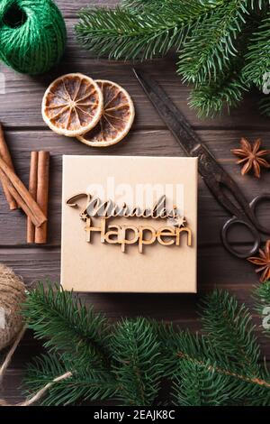Christmas gift box with wooden lettering miracles happen. Gifts wrapping ideas. Natural design. Stock Photo