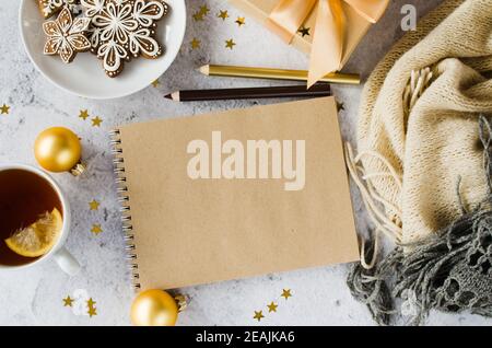 Flat lay of blank brown notebook with gift box, tea, cookies and plaid. Stock Photo