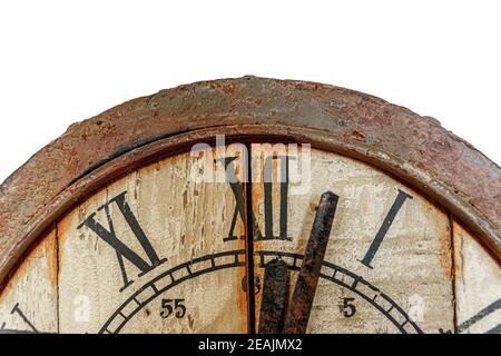 Old vintage and retro analogue clock displaying few minutes after twelve. Worn-out and grunge style with wooden background. Stock Photo