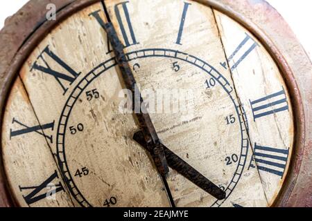 Old vintage and retro analogue clock displaying five minutes to twelve. Worn-out and grunge style. Stock Photo