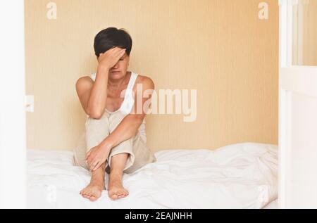 Woman sits in bed in her homemade pajamas. Women's health depression sleep problems sadness loneliness Stock Photo